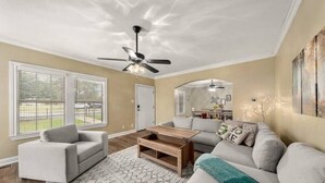 A living room with a ceiling fan, a sofa, a coffee table, and a patterned rug.