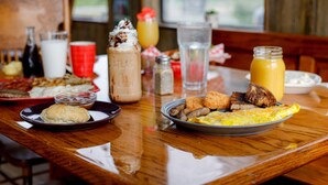A breakfast table with various dishes including eggs, sausages, toast, and a muffin.