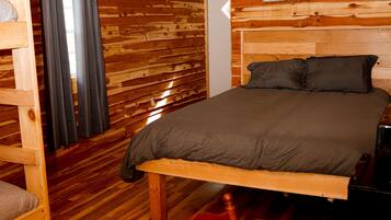 Una habitación tipo cabaña de madera con cama, una mesa y una silla.
