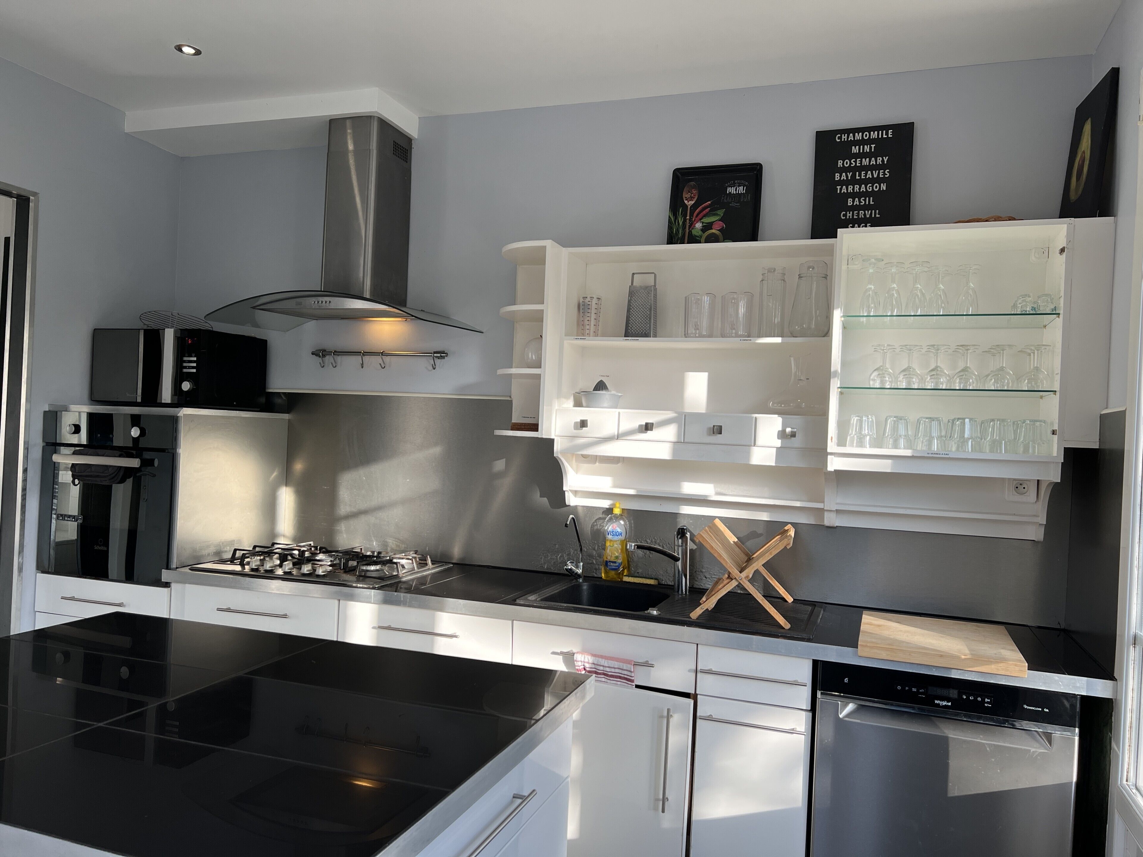 A modern kitchen with a black stove, stainless steel appliances, and a white cabinetry.