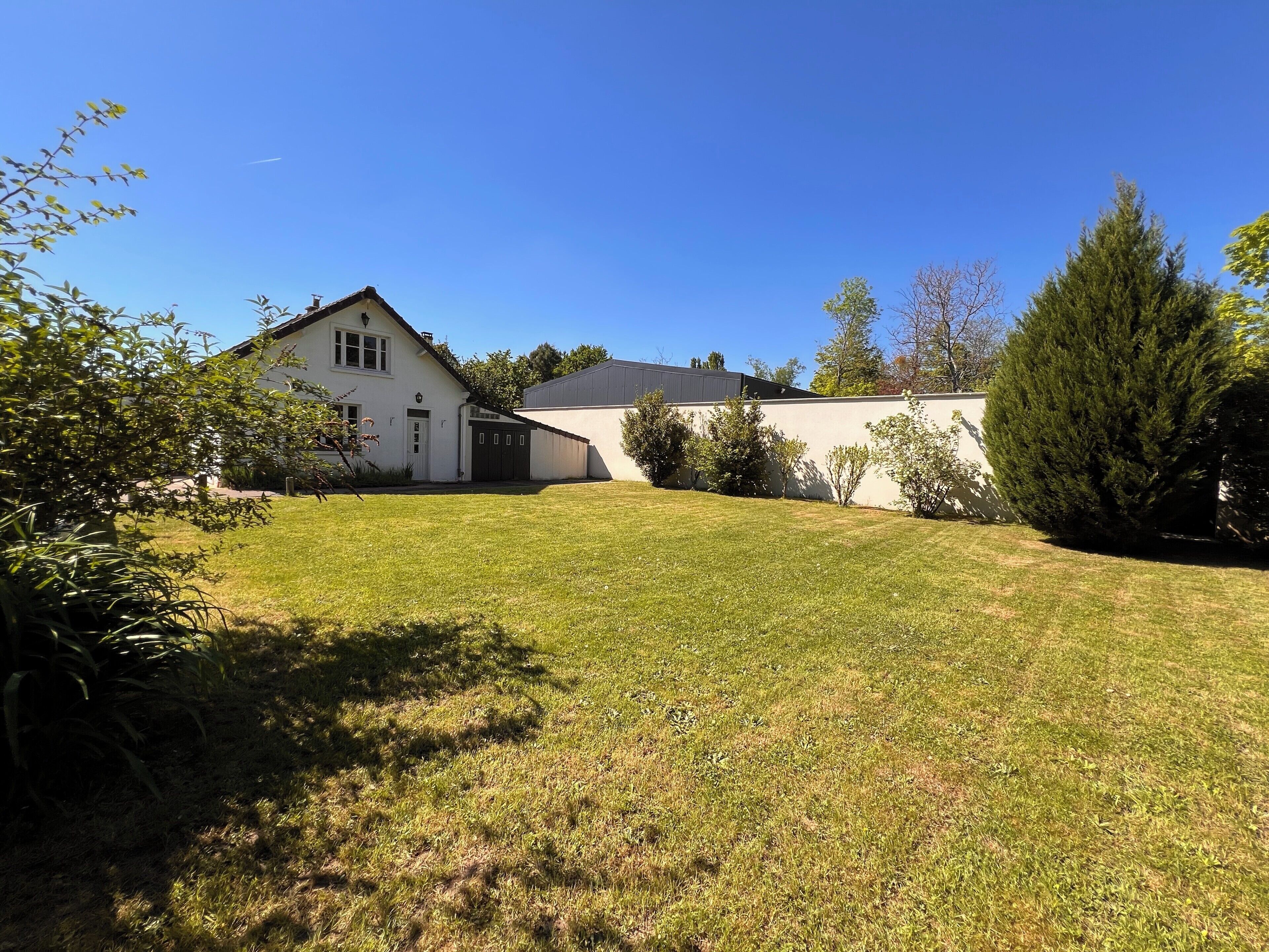 A residential property with a well-maintained lawn, a detached house, and a garage.