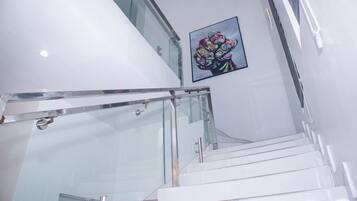 A modern staircase with glass railings and a white wall.