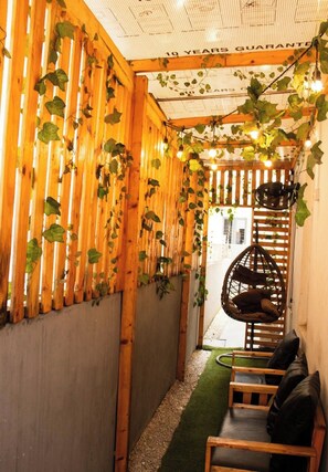 A narrow corridor with wooden slats and hanging plants, leading to a seating area with a hanging chair. - 4 Bedroom Fully Detached Duplex in Lekki, Lagos (Lekki)