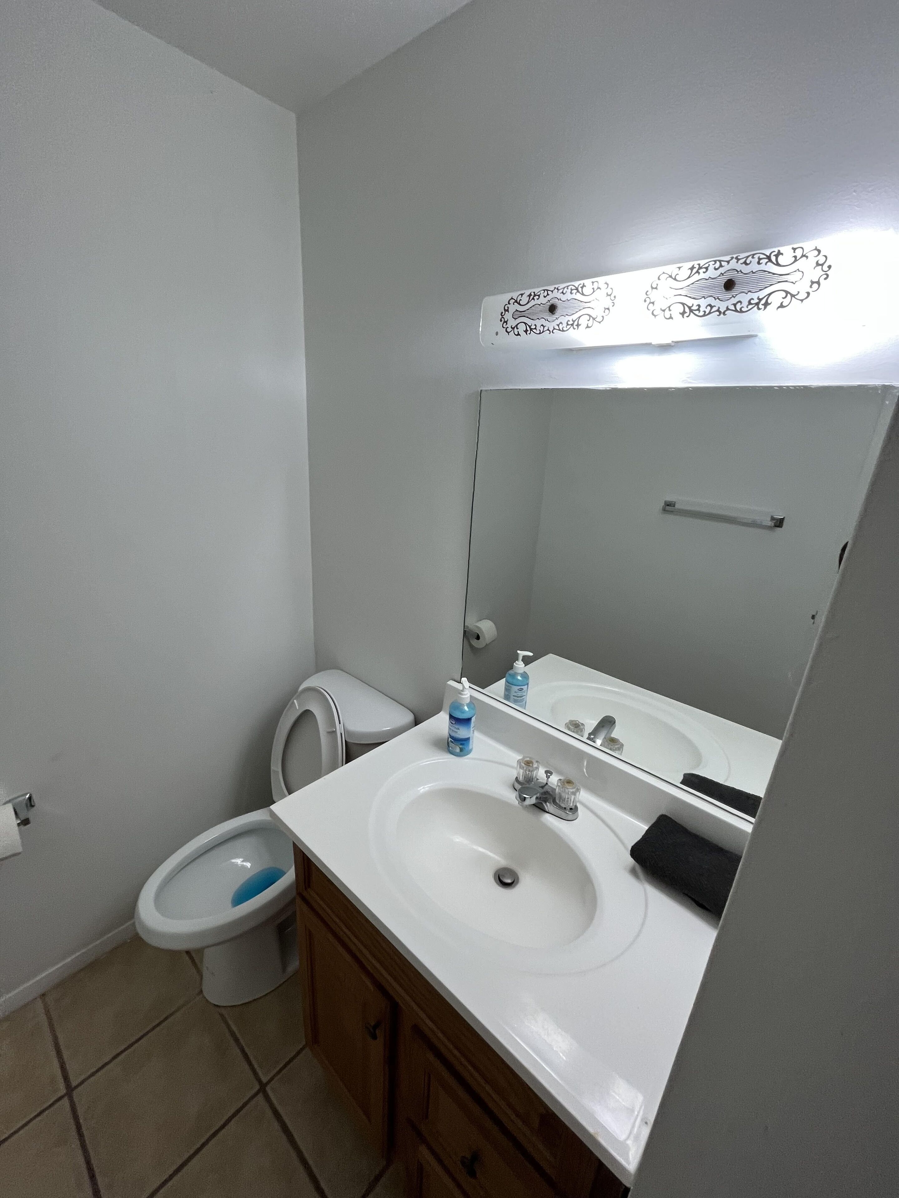 A bathroom with a white sink, mirror, and toilet.