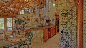 A rustic kitchen with stone walls, wooden beams, and a variety of kitchen utensils and decorations. - Hibiscus House Oceanfront Paradise in Fernandez Bay (New Bight)
