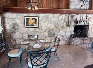A stone wall with a fireplace, a round glass table with chairs, and a framed picture.