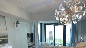 Un espace de salle à manger moderne avec une table en verre, des chaises blanches et un lustre original.