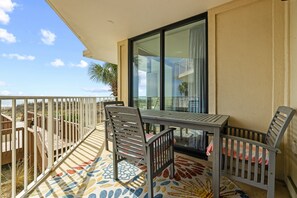 Ein Balkon mit Tisch und Stühlen, einem gemusterten Teppich und Blick auf den Strand.