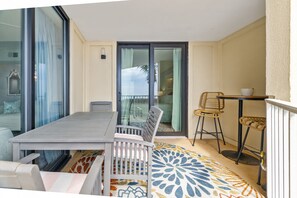 Ein Balkon mit Tisch und Stühlen, einer Schiebetür und einem gemusterten Teppich.