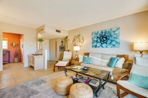 A living room with a sofa, armchairs, a coffee table, and a dining area with a small island.