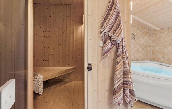 A wooden sauna room with a bench and a towel hanging on the wall.