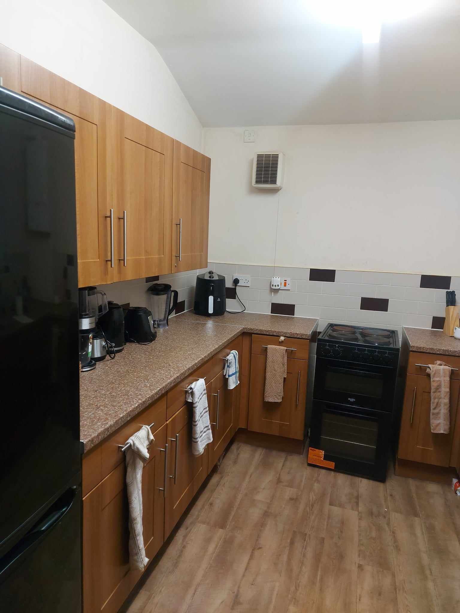A kitchen with wooden cabinets, a black stove, and a countertop with various appliances.