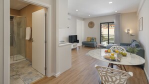 A modern living room with a dining area, a sofa, a TV, and a glass shower enclosure. - In the Funchal city center, Santa Luzia III (Funchal)