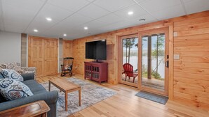 A wooden-paneled room with a sofa, a television, a cabinet, and a sliding glass door leading to a balcony.
