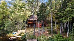 A cabin surrounded by trees, a dock, and a small dockless boat.