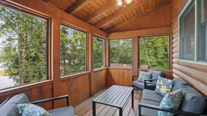 A wooden cabin with a porch, large windows, and a ceiling fan.