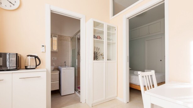 Habitación compacta con kitchenette, cama y baño.