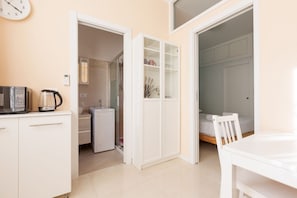 A compact room with a kitchenette, a bed, and a bathroom.