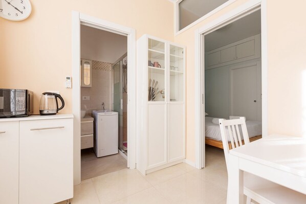 A compact room with a kitchenette, a bed, and a bathroom.
