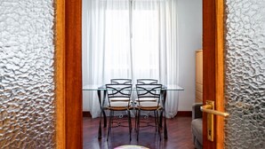 Ein Zimmer mit Glastisch und Stühlen, einem weißen Vorhang und einer Holztür.