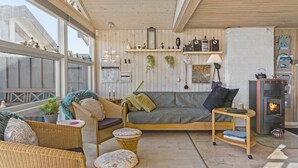 Un salon chaleureux avec un canapé, deux fauteuils en osier, une petite table et une cheminée.