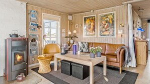 Un salon chaleureux avec un plafond en bois, une cheminée, un canapé, une table basse et deux tableaux accrochés au mur.