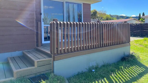 A residential property with a wooden deck, a sliding glass door, and a small set of stairs leading to the door.