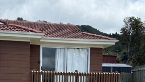 A single-story house with a red-tiled roof, a wooden deck, and a grassy yard.