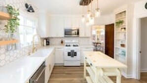Une cuisine moderne avec des meubles blancs, un îlot central et des appareils en acier inoxydable.