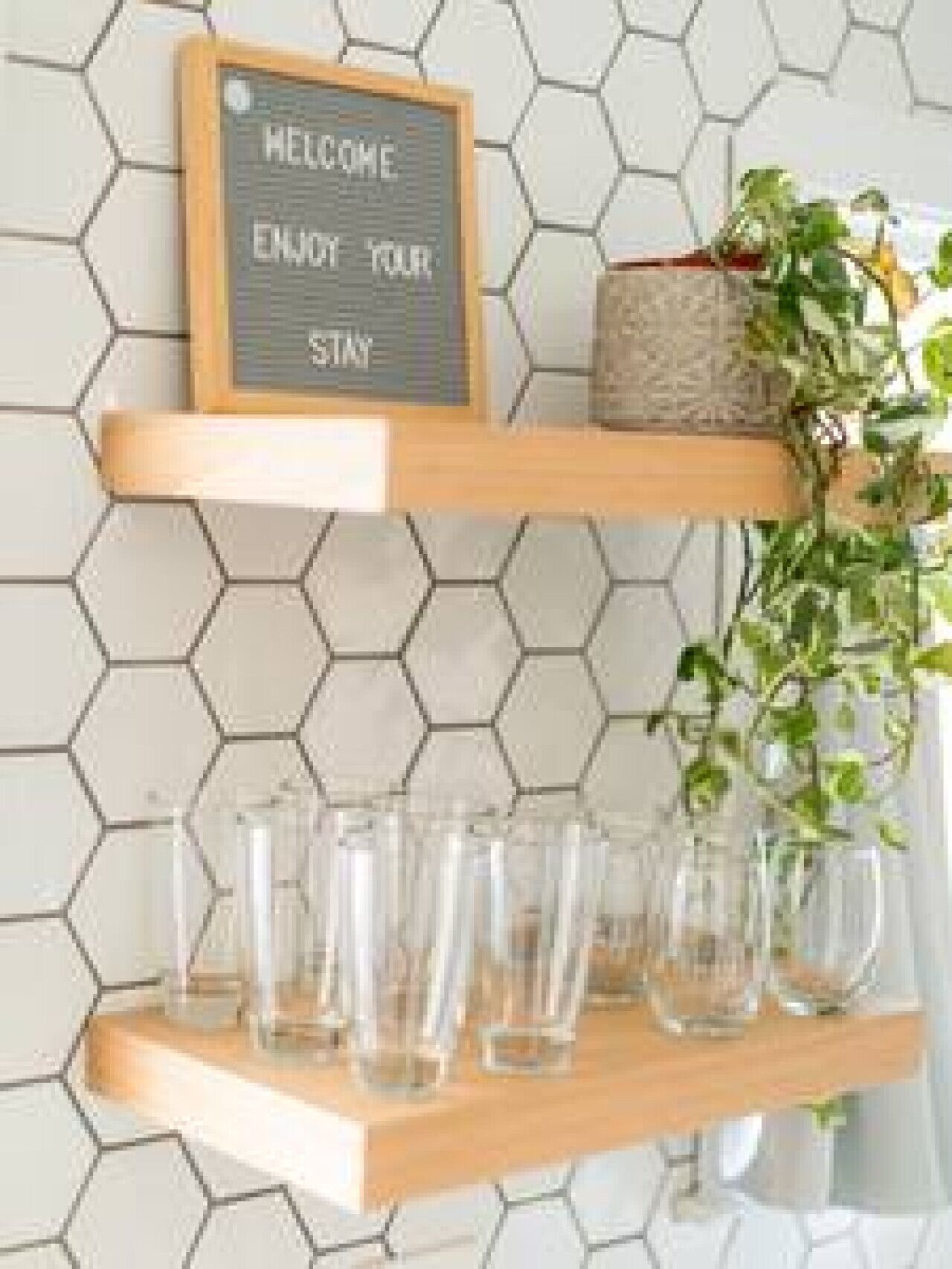 A sign with 'WELCOME ENJOY YOUR STAY' on a hexagonal tile wall.
