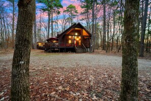 Une cabane dotée d’une véranda, entourée d’arbres.