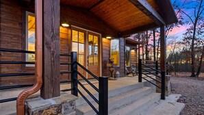 A wooden cabin with a stone staircase and a porch. - The Copper Hideout · Hochatown Hideout: Hot Tub, Fire Pit, Pure Relaxation (Broken Bow)