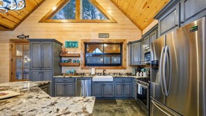 A modern kitchen with granite countertops, stainless steel appliances, and a large window above the sink. - The Copper Hideout · Hochatown Hideout: Hot Tub, Fire Pit, Pure Relaxation (Broken Bow)