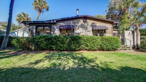 A two-story house with a covered porch, surrounded by well-maintained lawns and palm trees.