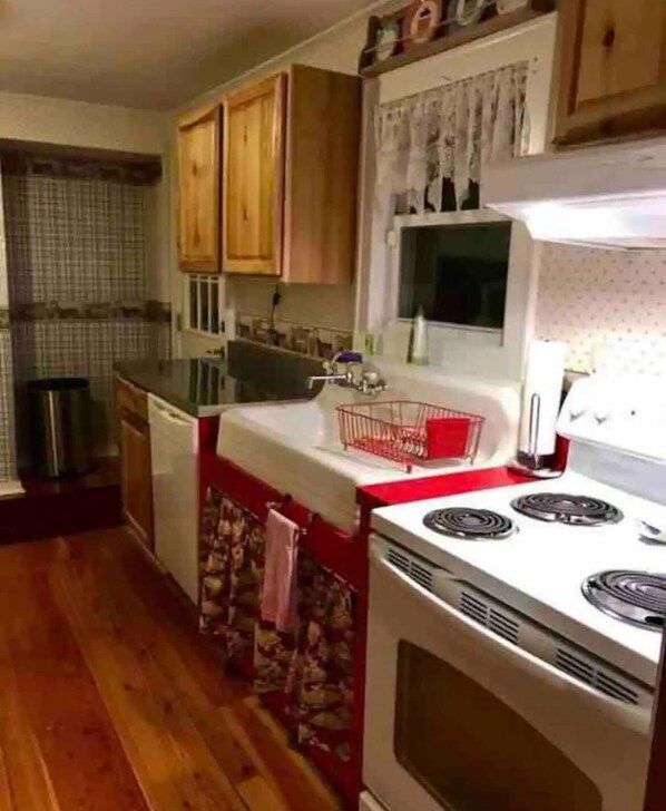 Una cocina compacta con armarios de madera, una estufa blanca y una encimera roja.