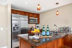 Eine moderne Küche mit Edelstahlgeräten, Holzschränken und einer Arbeitsplatte aus Granit.