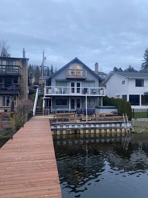 A waterfront property with a dock leading to a house with a balcony and outdoor seating. - Beautiful views, lakefront house ,  fun lake, hot tub, in scenic Skagit Valley. (Mount Vernon)