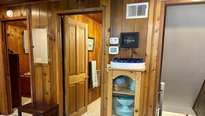Un interior de madera con un banco de madera, un aparador con platos azules y un cuadro de un pez en la pared.