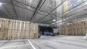 A covered parking area with bamboo walls and a metal roof structure.