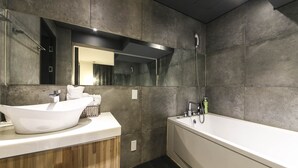 A modern bathroom with a freestanding bathtub, a vessel sink, and a large mirror.