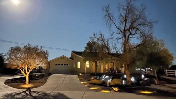 A residential area at night with houses, a parking lot, and a clear sky.