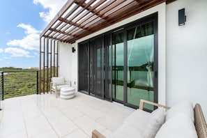 A balcony with a wooden pergola, a sofa, and a chair. - Márohu, 3BR Beach Oasis on Flamingo Lake (Venetian Road Settlement)