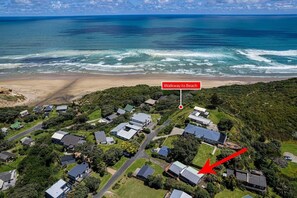 An aerial view of a residential area with houses, a marked walkway to the beach, and a red arrow pointing to a specific house. - Games room, 250mtrs to beach, spacious, comfy beds (Baylys Beach)