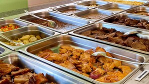 Een buffet met diverse gerechten, waaronder vlees, groenten en rijstmaaltijden.