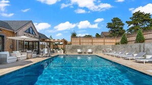 A swimming pool with lounge chairs and a covered seating area. - New Construction! 5 bedroom home with community clubhouse and pool (Nantucket)