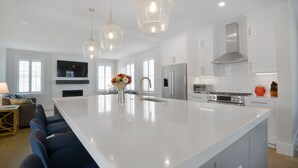 A spacious kitchen with a large island, white cabinetry, stainless steel appliances, and pendant lighting. - New Construction! 5 bedroom home with community clubhouse and pool (Nantucket)