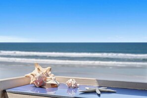 Un banco de madera con caracoles y una estrella de mar, con vista al océano.