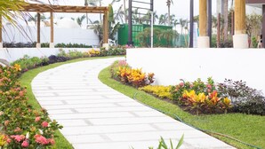 A curved pathway with a garden on one side and a white wall on the other. - Luxury Diamante Apartment, Private Beach Club, 4 Bedrooms, 8 Guests (Acapulco de Juárez)