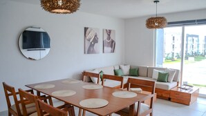 A modern living room with a dining table, sofa, and artwork on the wall. - Luxury Diamante Apartment, Private Beach Club, 4 Bedrooms, 8 Guests (Acapulco de Juárez)