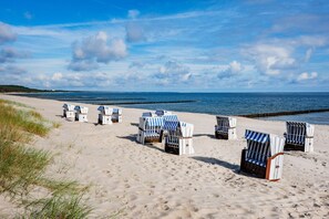 Ein Strand mit Reihen aus Liegestühlen und Sonnenschirmen, einige mit Nummern versehen.